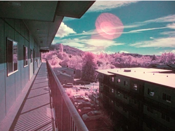 False color infrared photo looking down an exterior hallway of an apartment building.