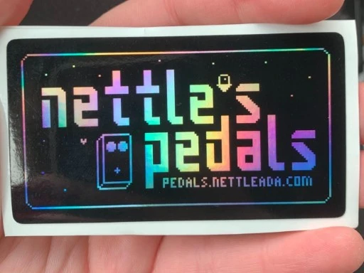 Photograph of a shiny holographic sticker that says Nettle's Pedals